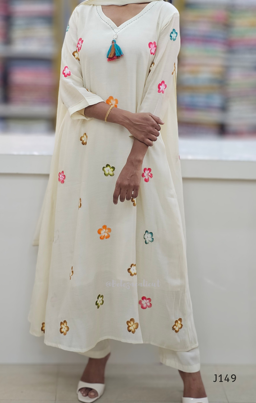 Woman wearing a cream-colored kurta with floral embroidery in a store setting