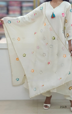 Person wearing a white embroidered outfit with colorful floral patterns on a blurred background