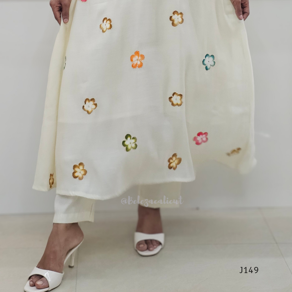 White outfit with floral embroidery held by a person on a white background