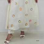 White outfit with floral embroidery held by a person on a white background