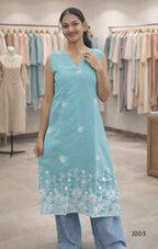 Woman wearing a light blue embroidered kurta in a clothing store.