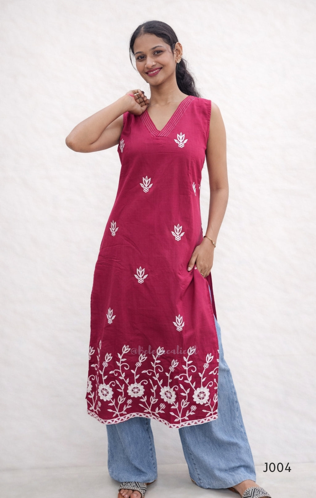 Woman wearing a pink kurta with white floral patterns on a plain background