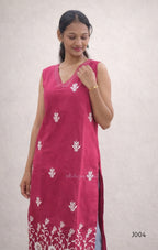Woman wearing a pink sleeveless dress with white floral patterns on a plain background