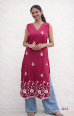 Woman wearing a red kurta with white floral patterns on a plain background