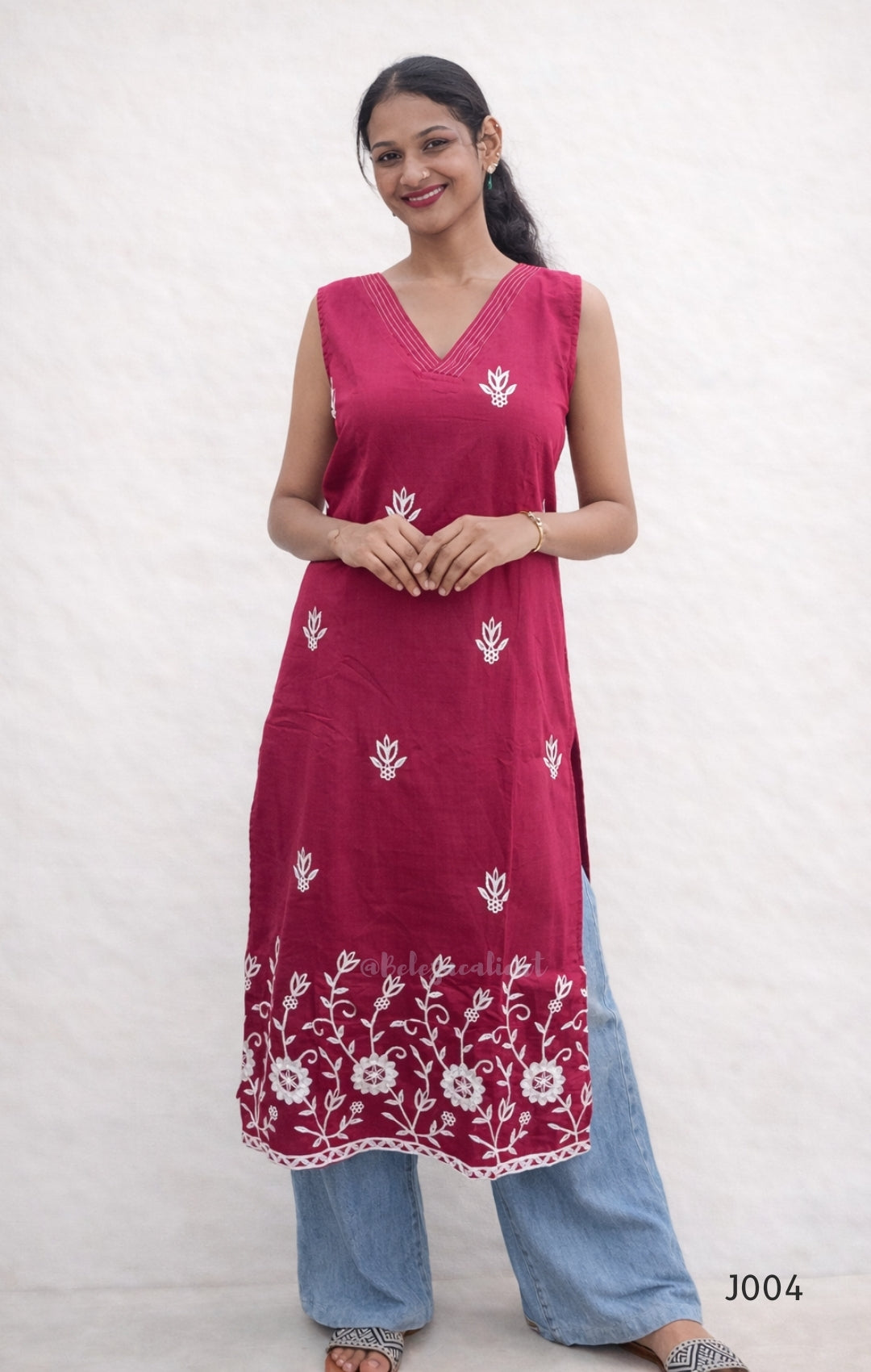 Woman wearing a red kurta with white floral patterns on a plain background