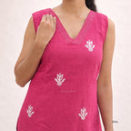 Pink sleeveless top with white floral patterns on a plain background