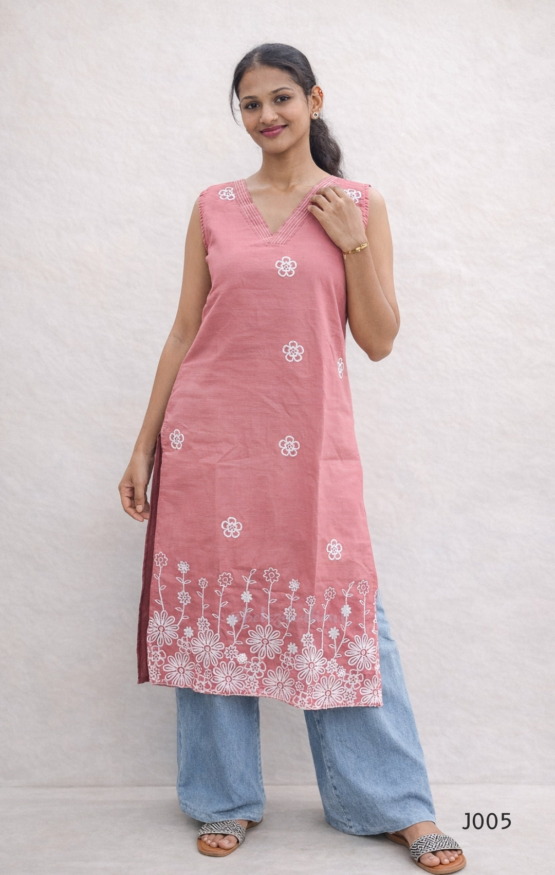 Woman wearing a pink kurta with white floral patterns on a plain background