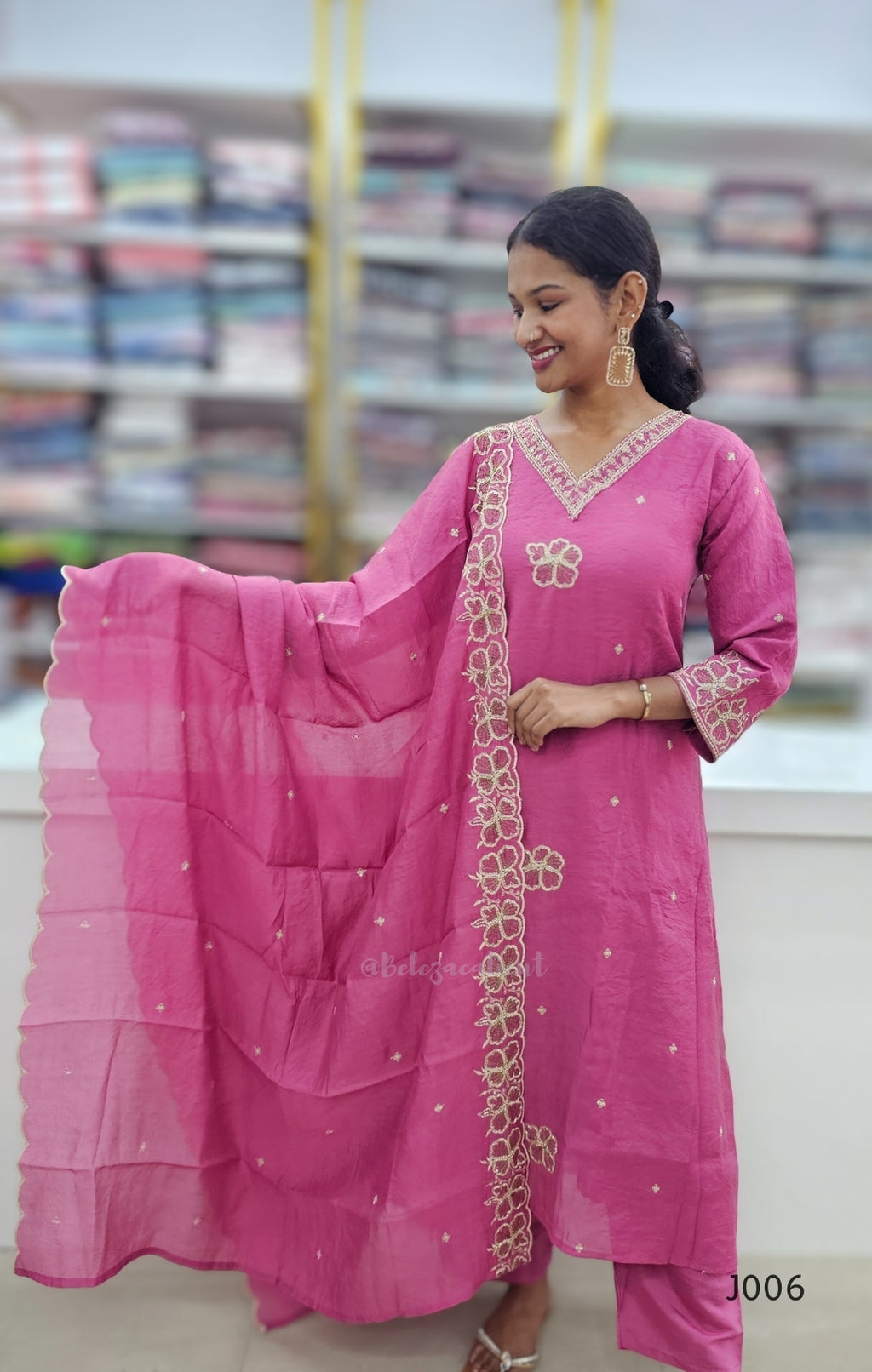Woman wearing a pink traditional outfit with a matching dupatta in a store setting.