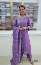 Woman wearing a purple traditional outfit with a matching dupatta in a store setting.