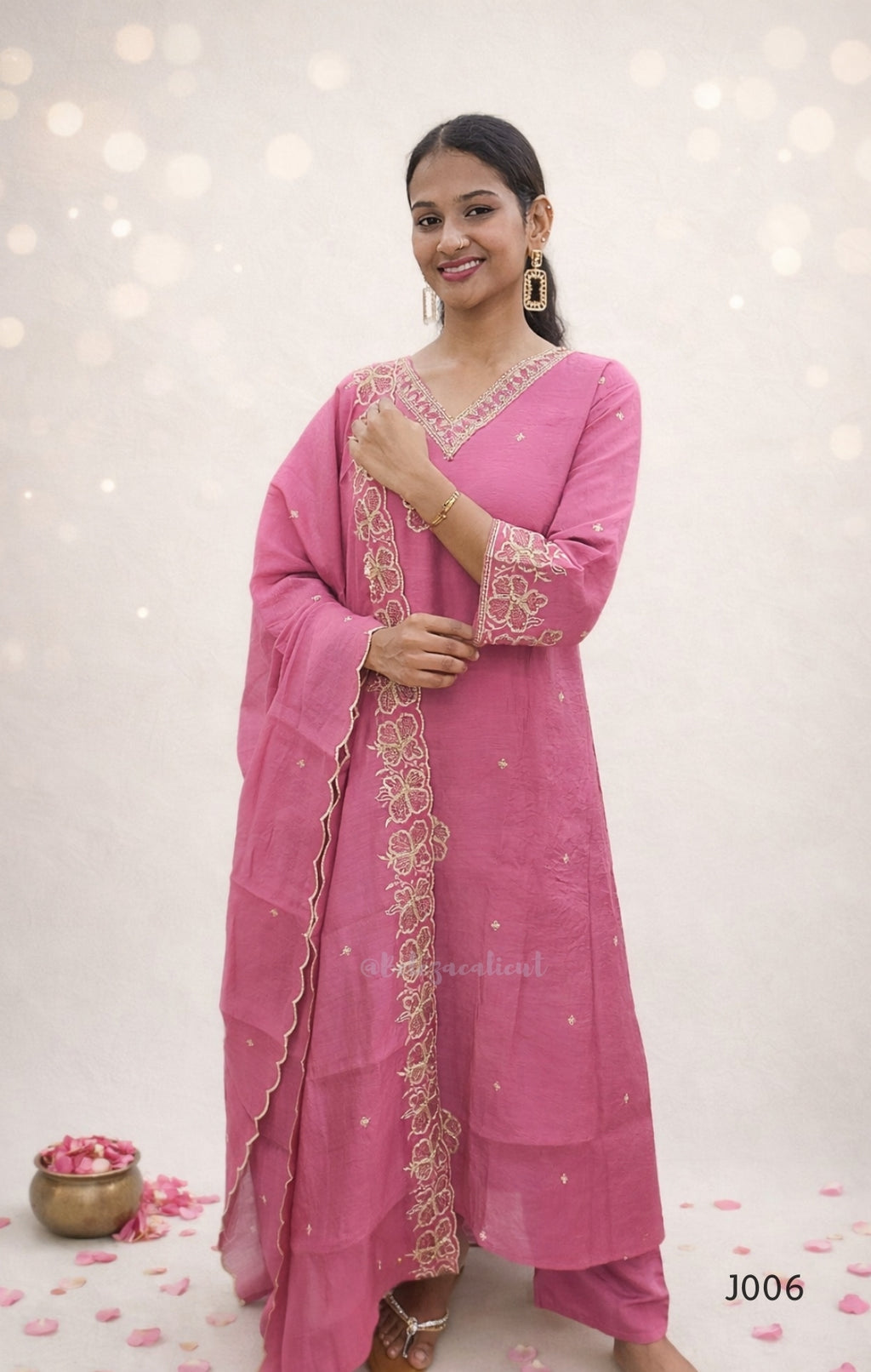 Woman wearing a pink traditional outfit with intricate designs on a light background