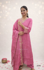 Woman wearing a pink traditional outfit with intricate designs on a light background