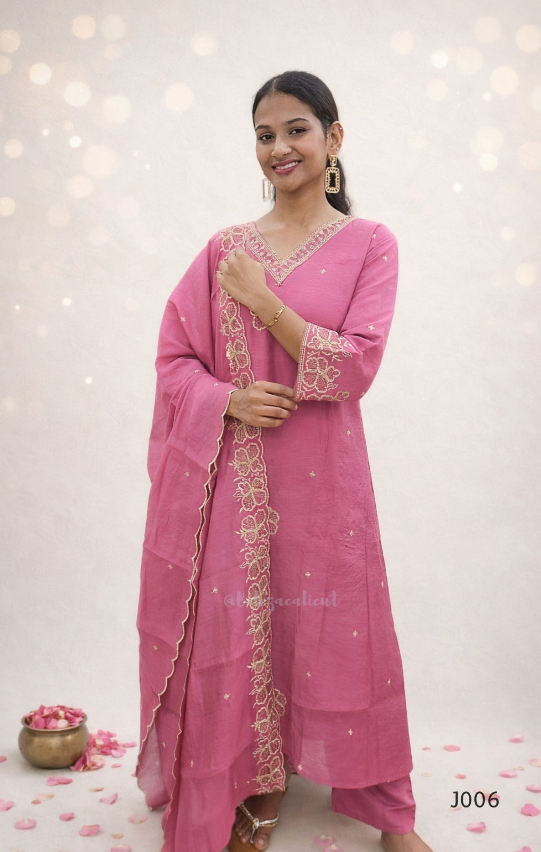 Woman wearing a pink traditional outfit with intricate designs on a light background