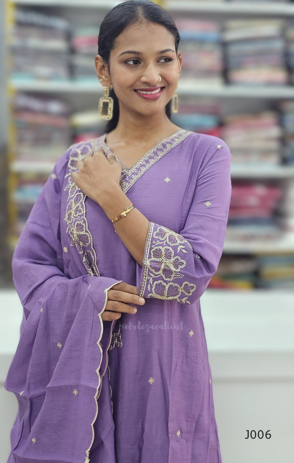 Woman wearing a purple traditional outfit with gold embroidery in a bookstore setting