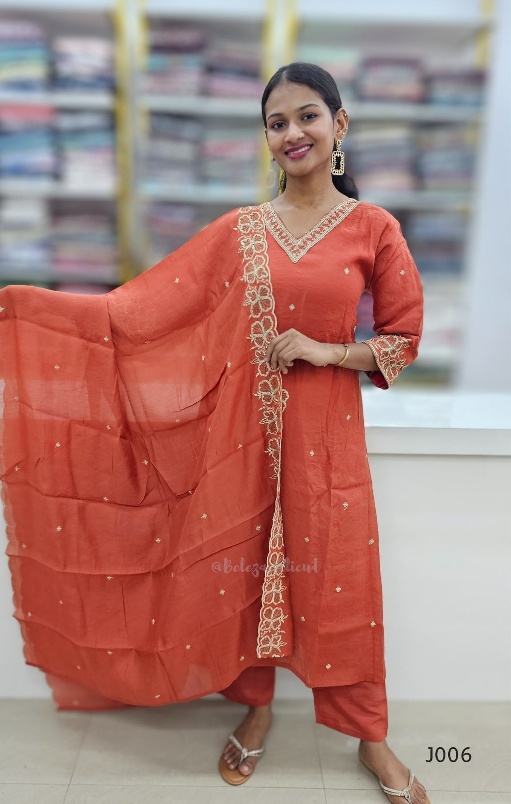 Woman wearing an orange traditional outfit with a dupatta in a store setting