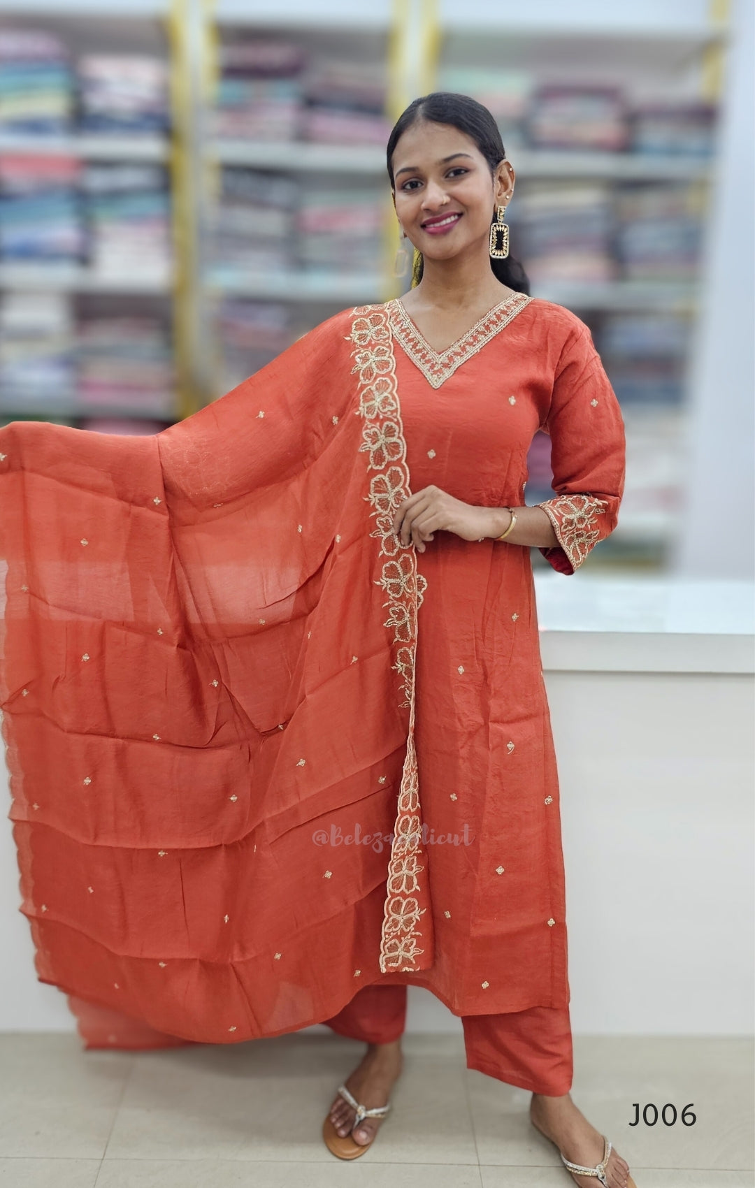 Woman wearing an orange traditional outfit with a dupatta in a store setting