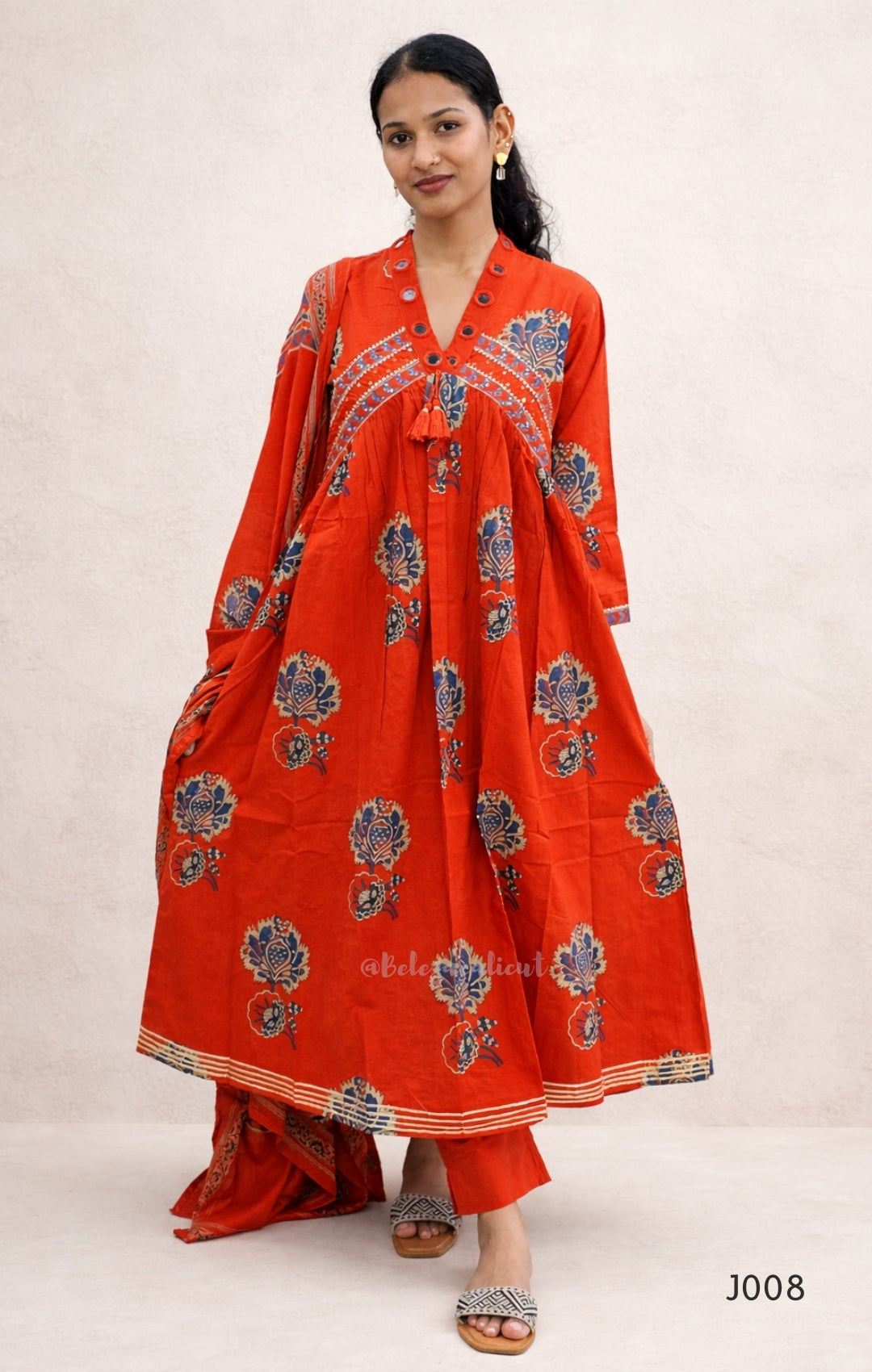 Woman wearing a red traditional outfit with floral patterns on a white background