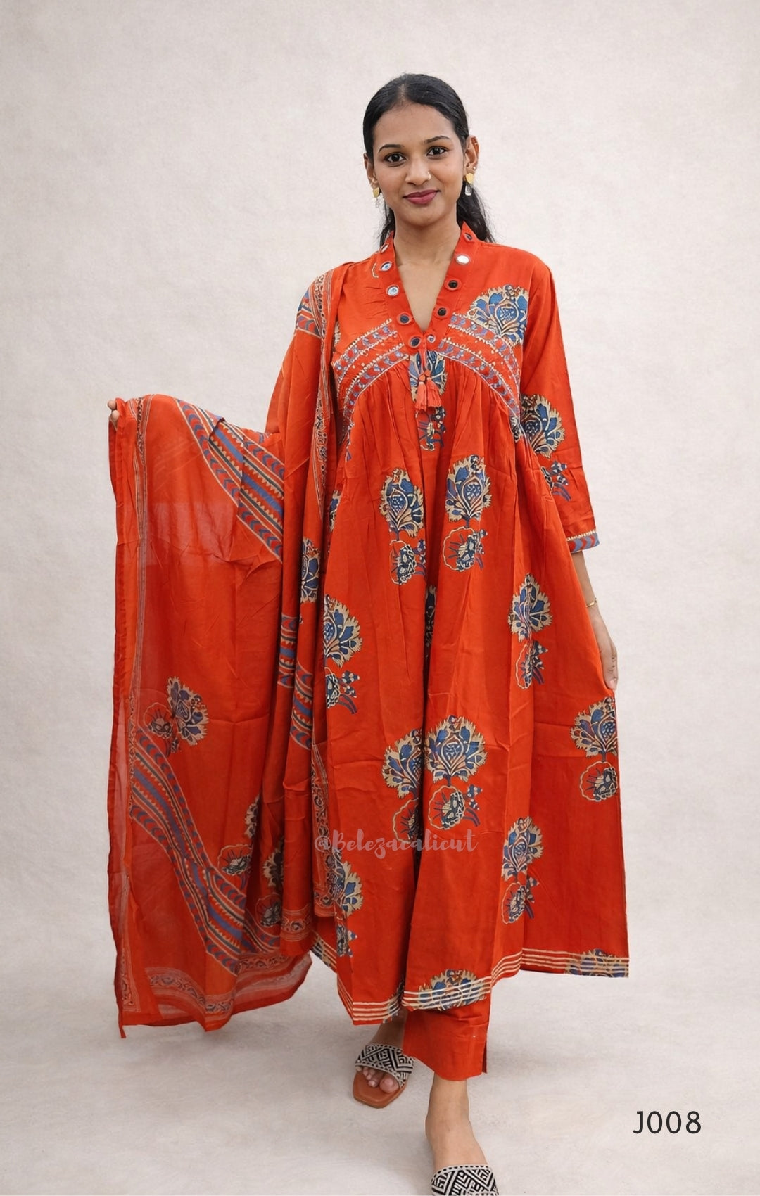 Woman wearing a red traditional outfit with floral patterns on a plain background