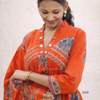 Woman wearing an orange traditional outfit with intricate patterns on a plain background