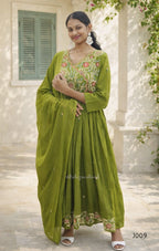 Woman wearing a green traditional outfit with floral patterns in an outdoor setting.