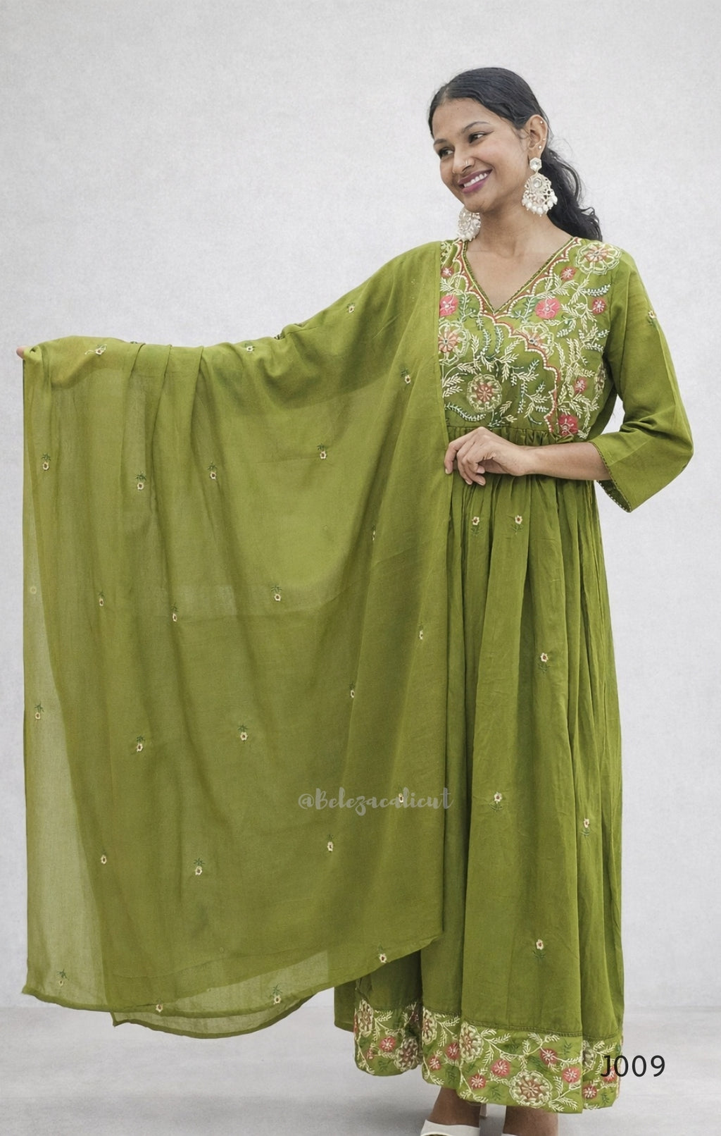Woman wearing a green traditional outfit with a matching dupatta on a white background