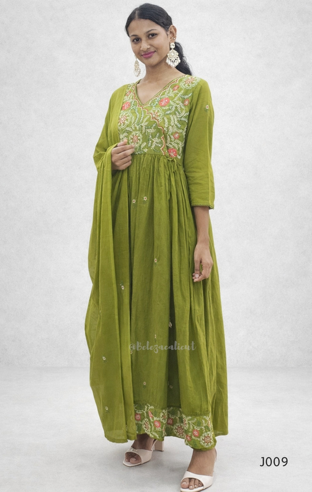 Woman wearing a green embroidered dress on a white background