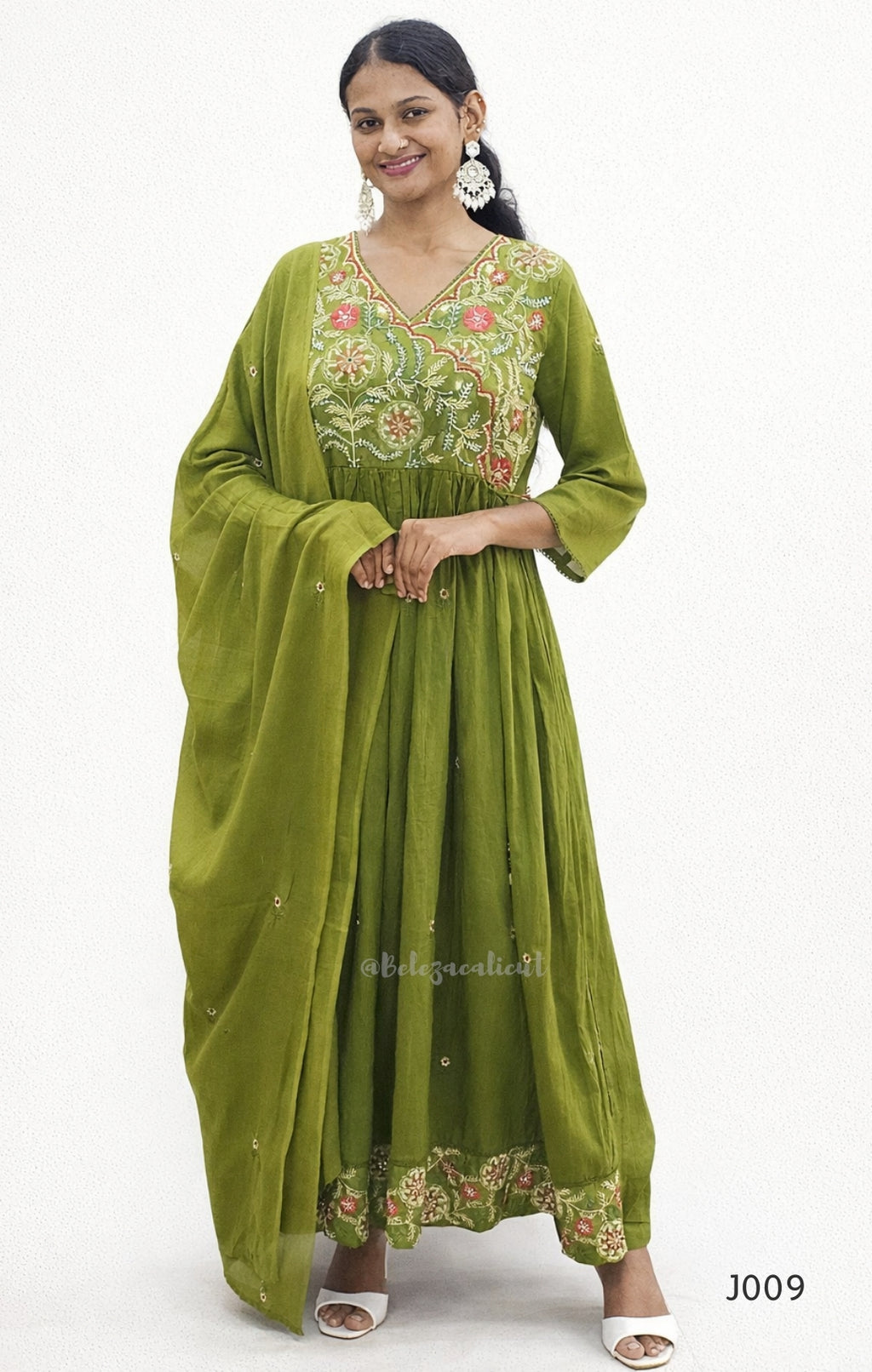 Woman wearing a green embroidered traditional outfit on a white background