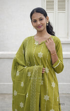 Woman wearing a green traditional outfit with white patterns against a white background