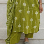 Green traditional outfit with white floral patterns on a neutral background