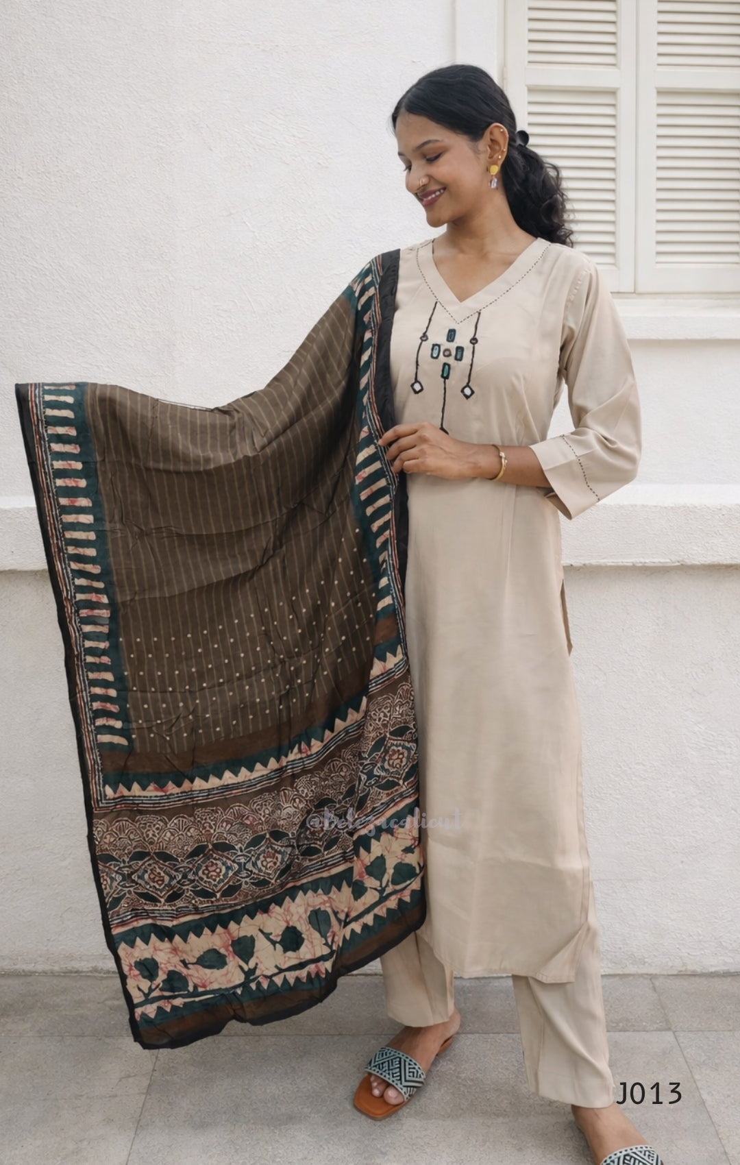 Woman holding a patterned scarf in front of a white wall
