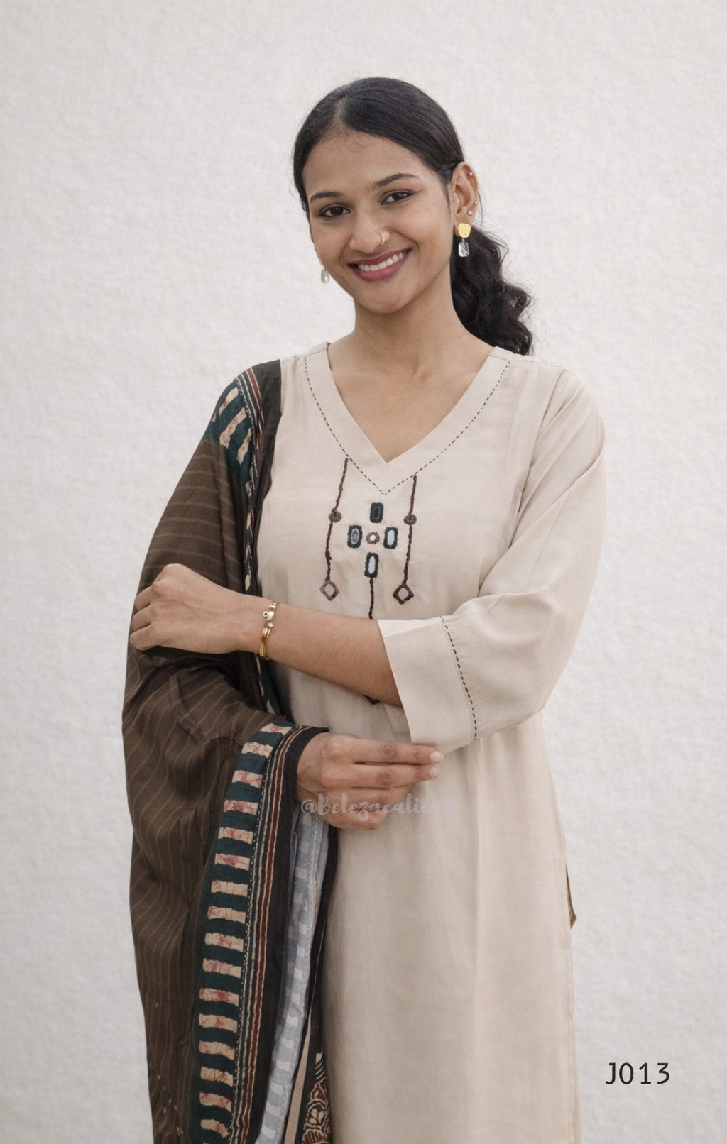 Woman wearing a beige kurta with a brown dupatta against a white background