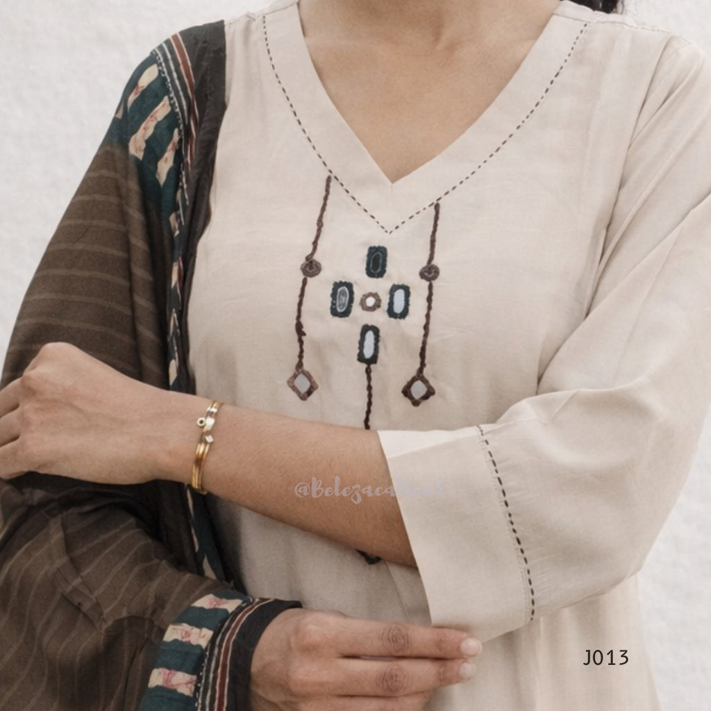 Close-up of a person wearing a beige embroidered top with a patterned shawl.
