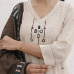 Close-up of a person wearing a beige embroidered top with a patterned shawl.