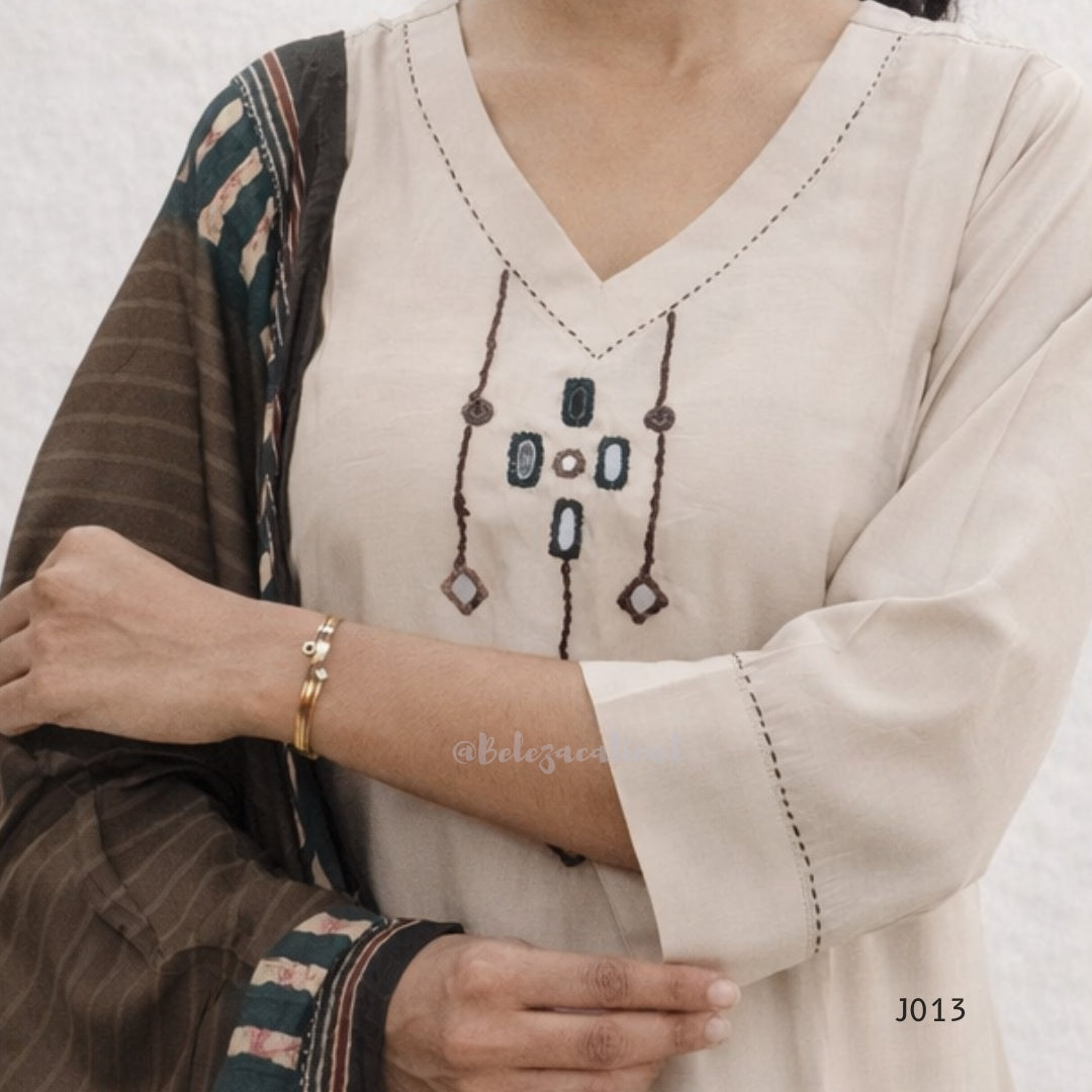 Close-up of a person wearing a beige embroidered top with a patterned shawl.