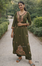 Woman wearing a green embroidered traditional outfit standing outdoors.