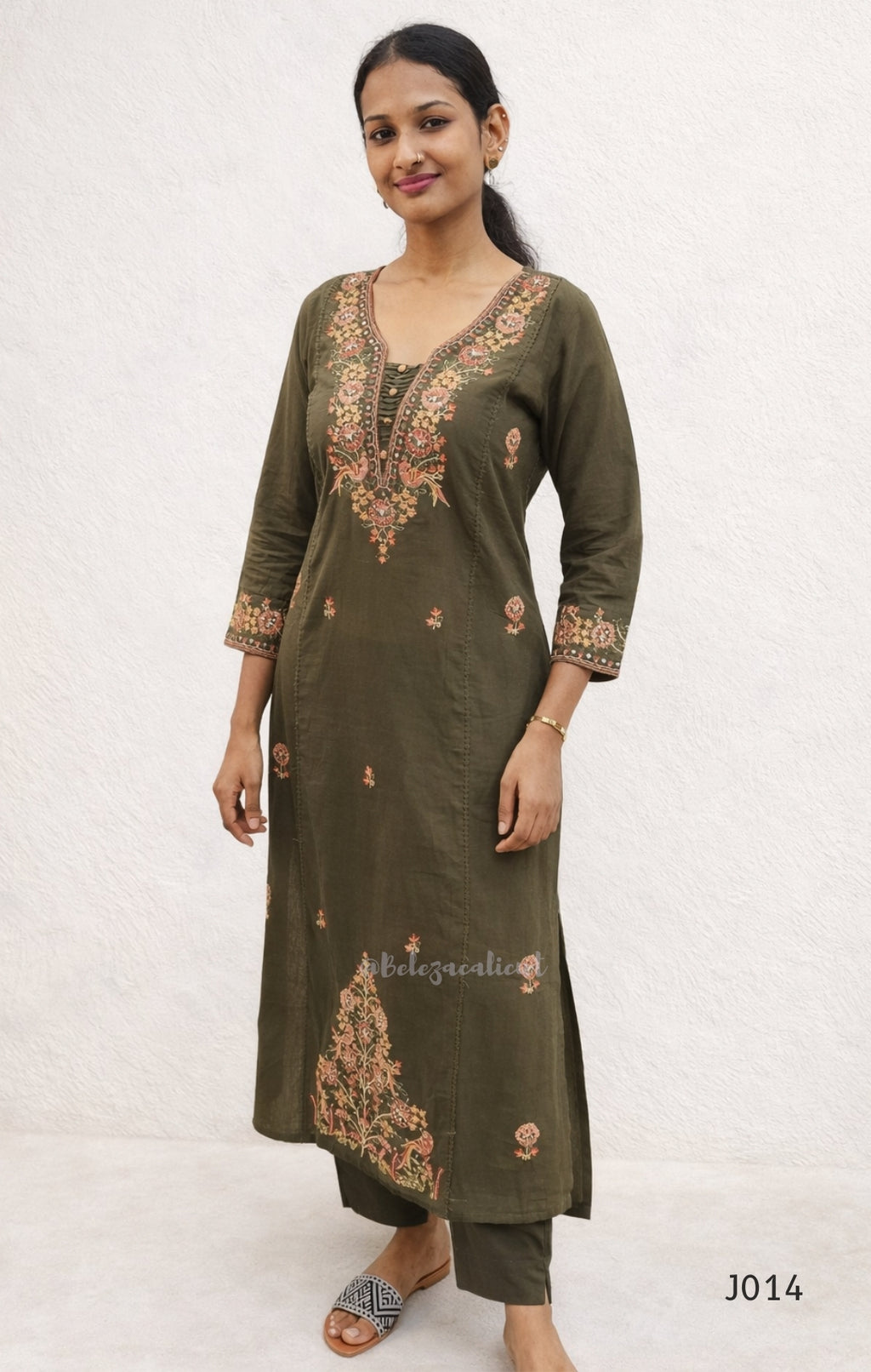 Woman wearing a green embroidered kurta with a plain white background
