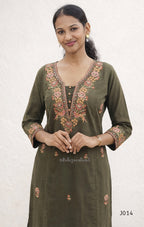 Woman wearing a green embroidered traditional outfit on a white background
