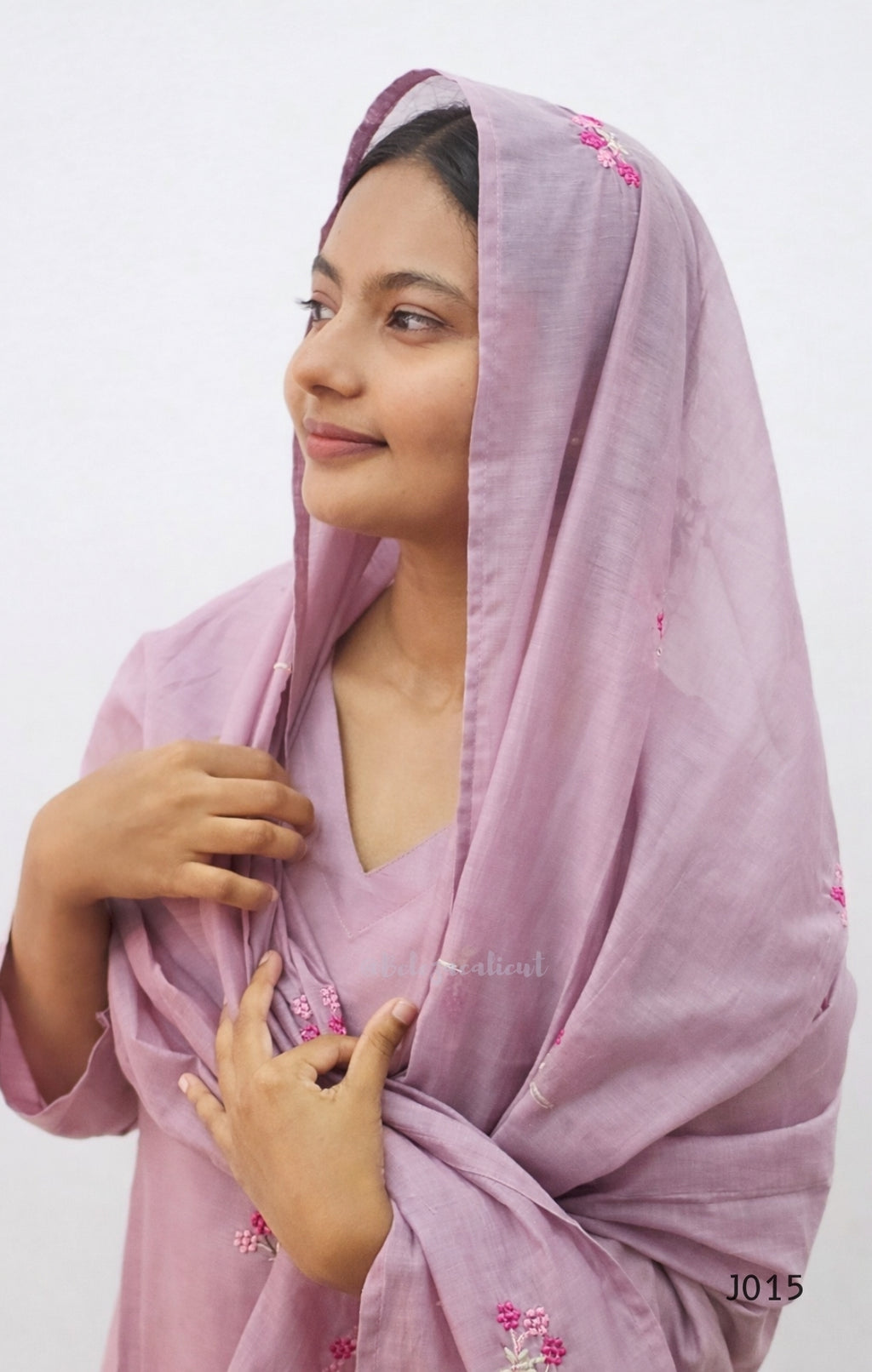 Woman wearing a light purple scarf with floral patterns on a white background