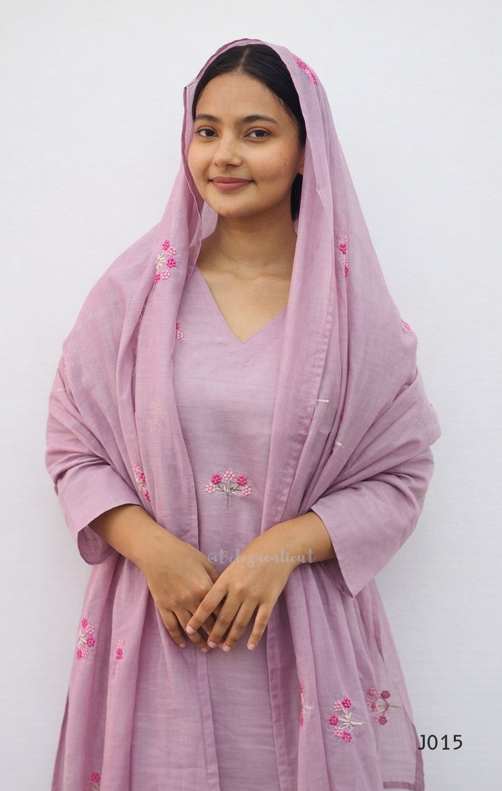 Woman wearing a pink embroidered dupatta and dress against a white background