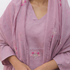 Pink traditional outfit with floral embroidery on a plain background