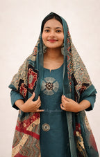 Woman wearing a teal dress with a patterned shawl on a white background