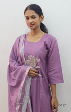 Woman wearing a purple traditional outfit with white embroidery on a plain background