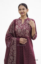 Woman wearing a maroon traditional outfit with floral patterns on a white background