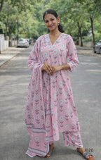 Woman wearing a pink floral outfit standing on a street.