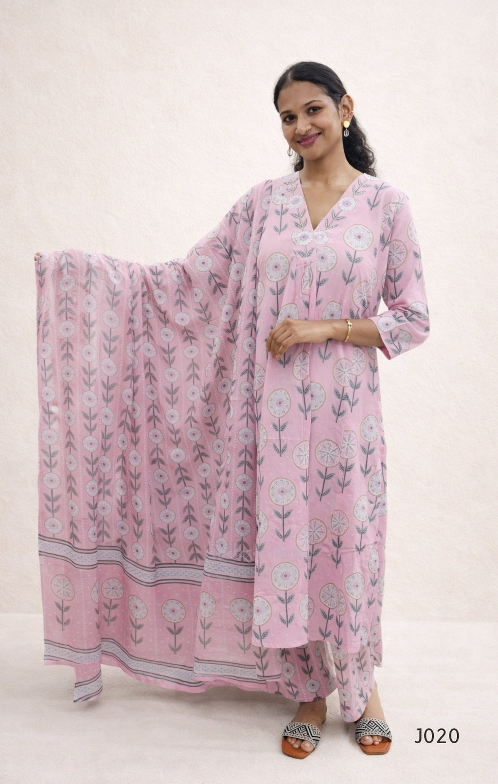 Woman wearing a pink floral dress with a matching dupatta on a white background