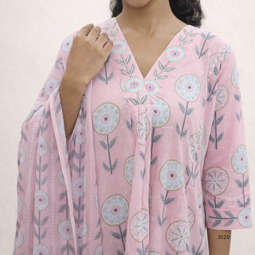 Person wearing a pink floral dress with a plain background