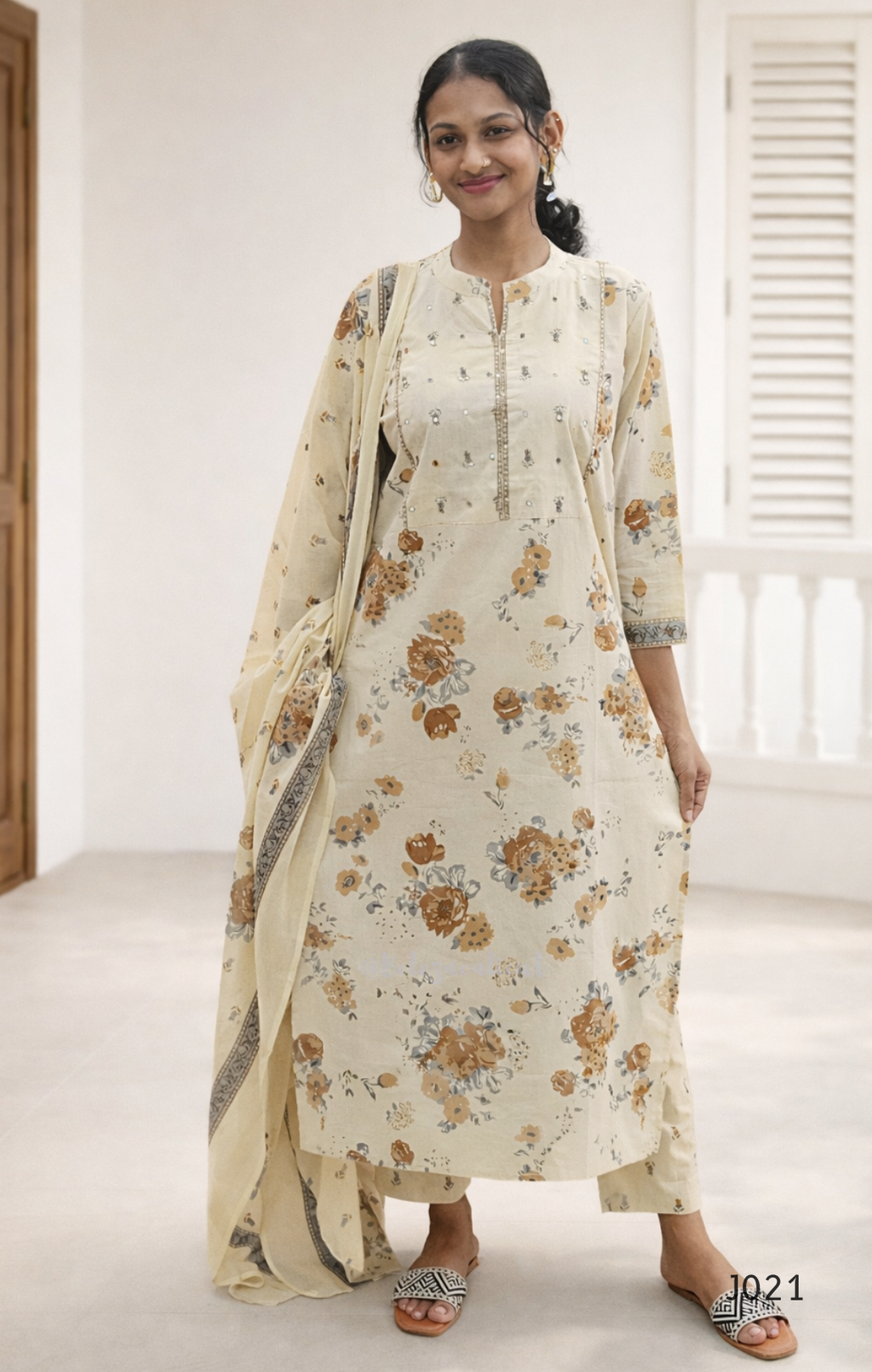 Woman wearing a floral dress with a matching dupatta in a bright room.