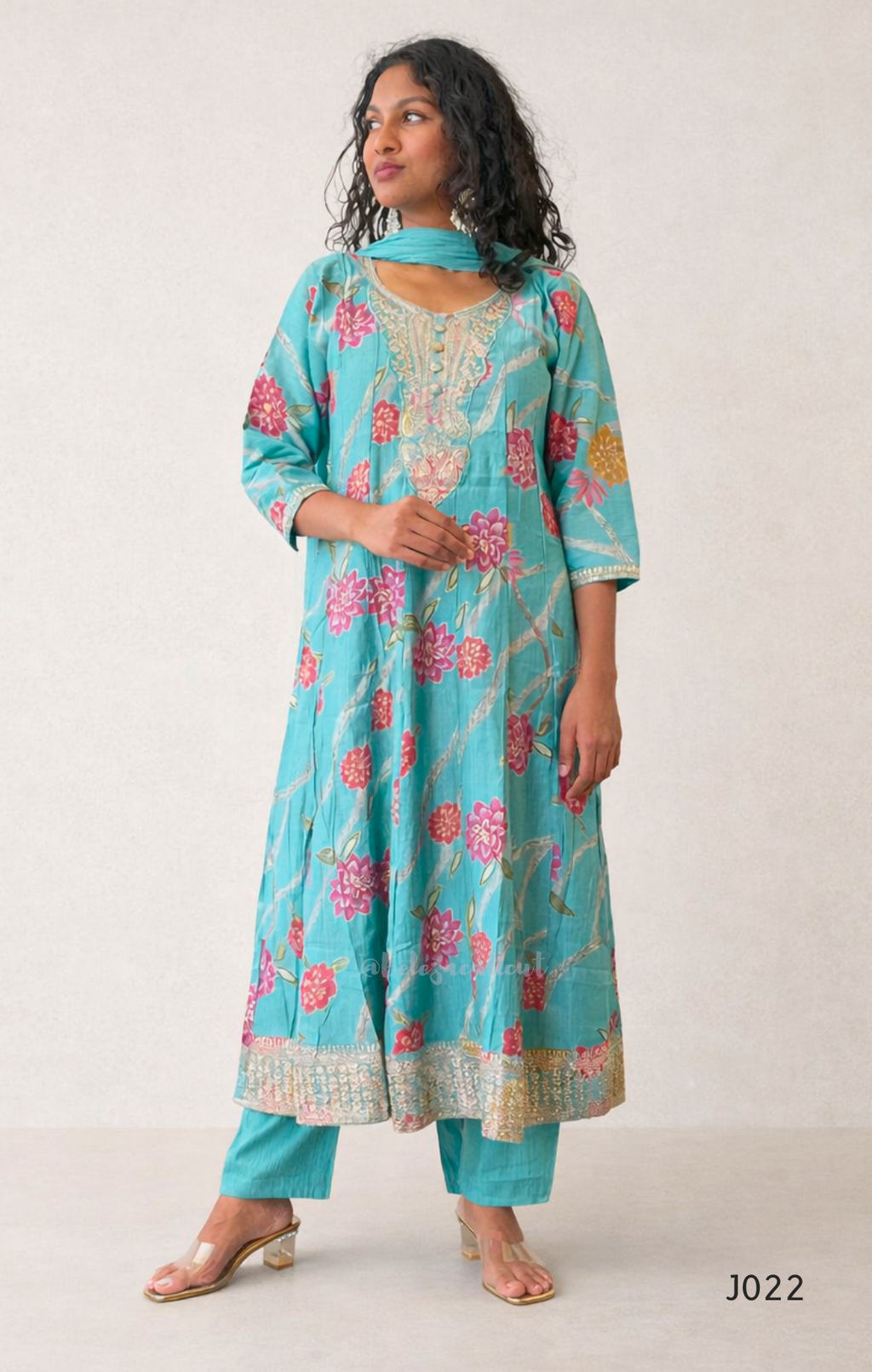 Woman wearing a turquoise floral traditional outfit on a white background