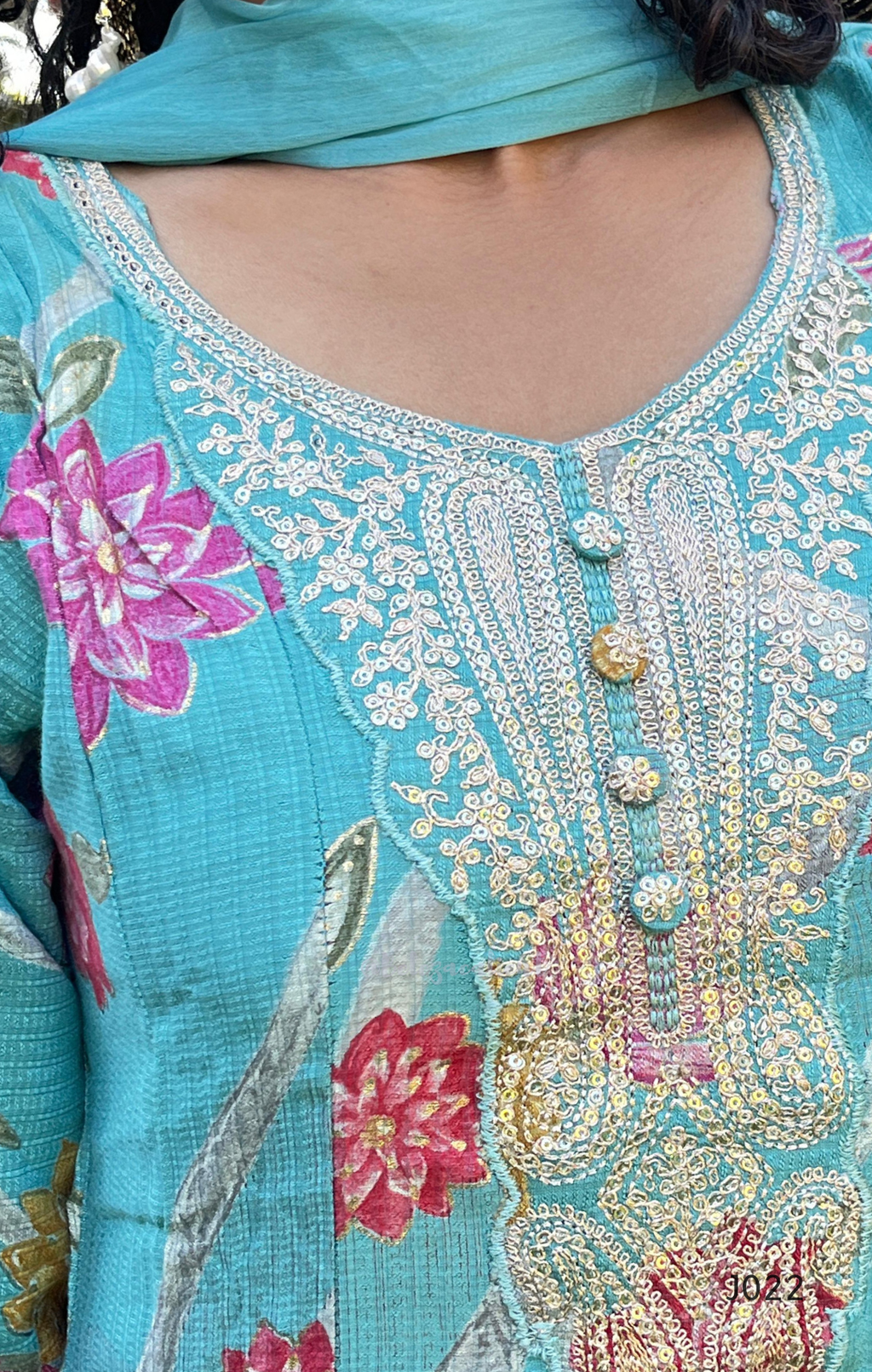 Close-up of a turquoise embroidered garment with floral patterns