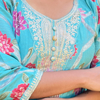 Close-up of a turquoise embroidered garment with floral patterns