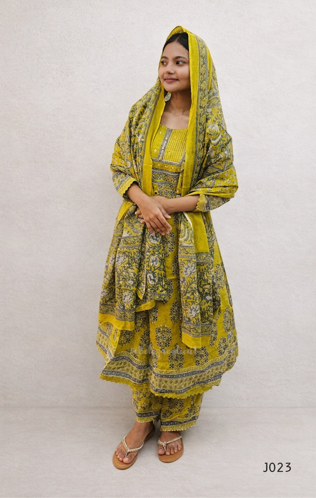 Woman wearing a yellow traditional outfit with a matching dupatta on a white background